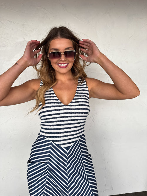 Woman wearing a black and white striped dress with sunglasses against a white background