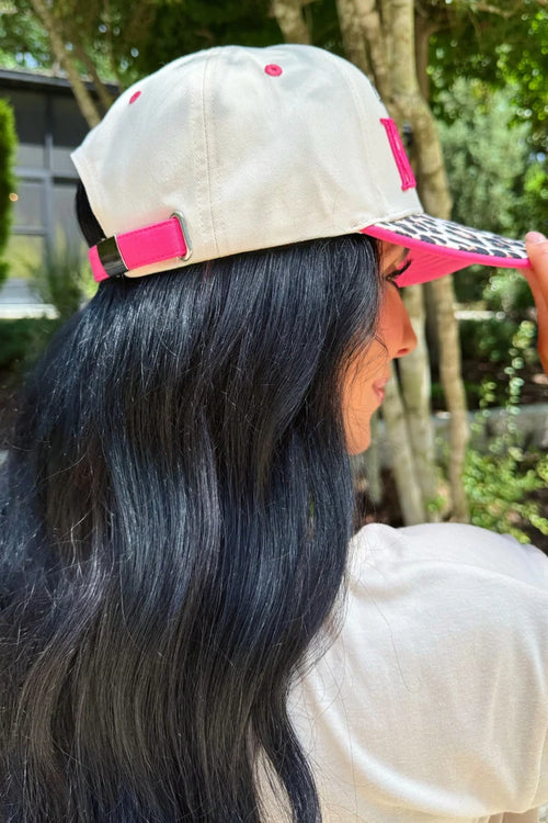 Person wearing a beige cap with pink accents outdoors