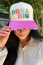 Person wearing a colorful 'Dream Big' cap with a pink brim.