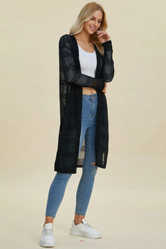 Woman wearing a black long-sleeve top, white tank top, blue jeans, and white sneakers on a beige background
