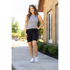 Front full-body shot of model in high-waisted black biker shorts and a grey ribbed tank top, styled for a casual outdoor workout or errand run.