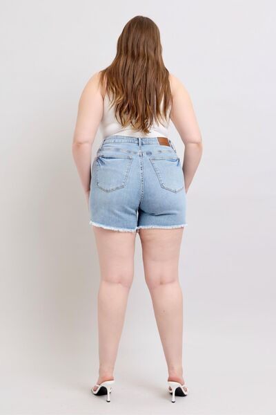  Back view of plus-size raw hem denim shorts, displaying flattering fit and coverage.