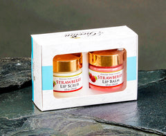 Two strawberry lip products in a box on a dark stone surface