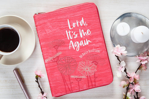 Pink devotional book titled 'Lord, It's Me Again' on a table with coffee and flowers.