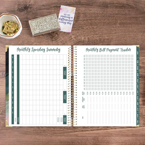Open planner showing monthly spending summary and bill payment tracker on a wooden surface.