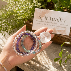 Hand holding crystal bracelets with a card about spirituality in a natural setting