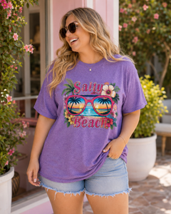 Woman wearing a purple 'Salty Beach' t-shirt with sunglasses and palm tree design.