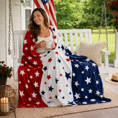 Woman sitting on a white porch swing wrapped in a red, white, and blue patriotic stars fleece throw blanket while holding a mug outdoors.