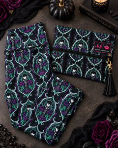 A gothic-themed two-piece set featuring a matching pair of leggings and a zippered pouch. The fabric has a black background with a repeating pattern of purple roses, green leaves, and white skulls framed by teal baroque scrolls.