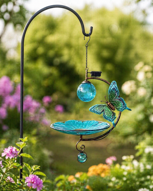 Decorative garden ornament with butterfly design and glass elements in a garden setting.