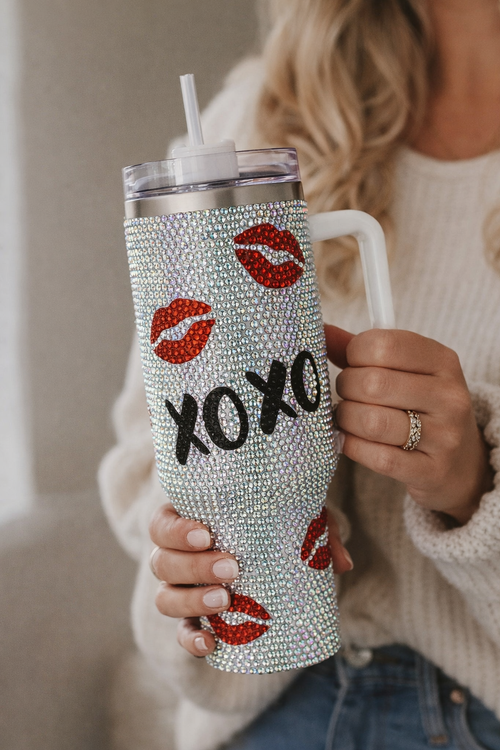Person holding a blinged-out tumbler with 'XOXO' and lip prints.