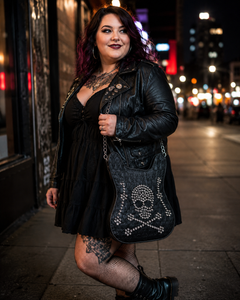 Woman in a black leather jacket with a skull design bag on a city street at night.