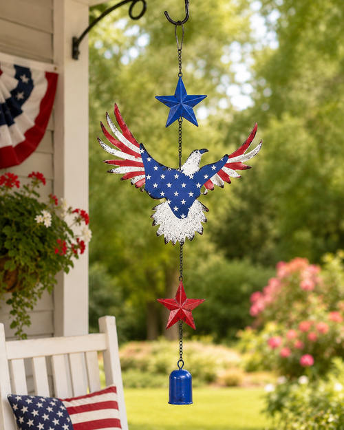 Patriotic eagle hanging chime displayed on a porch with red white and blue bunting, flowers, and an American flag pillow.