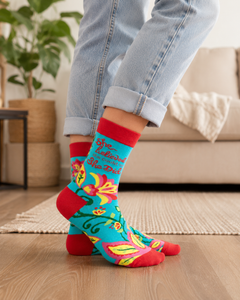 Close-up of woman wearing cuffed jeans and colorful women’s crew socks with red accents, floral details, and the phrase She Believed She Could, So She Did.