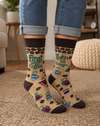 Beige women’s novelty crew socks with brown cuff, heel, and toe featuring the phrase First the Coffee Then the Things with coffee cups and coffee bean accents.