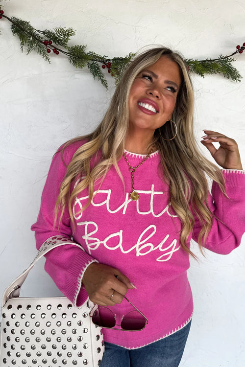 Woman wearing a pink 'Santa Baby' sweater with a white background