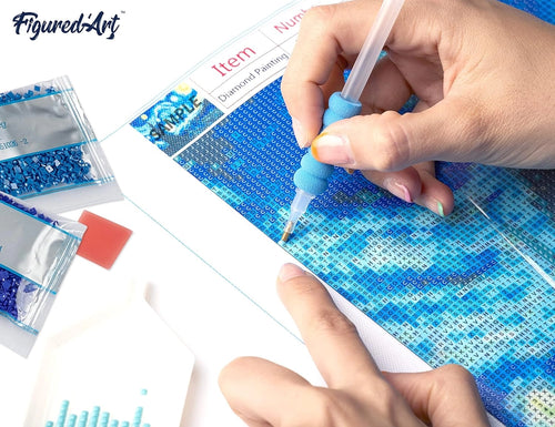 Person using a diamond painting tool on a blue and white grid
