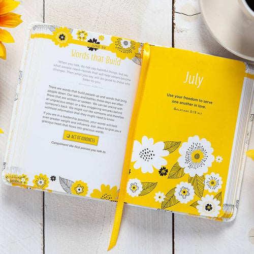 Yellow floral notebook open to a page with text on a white wooden surface.