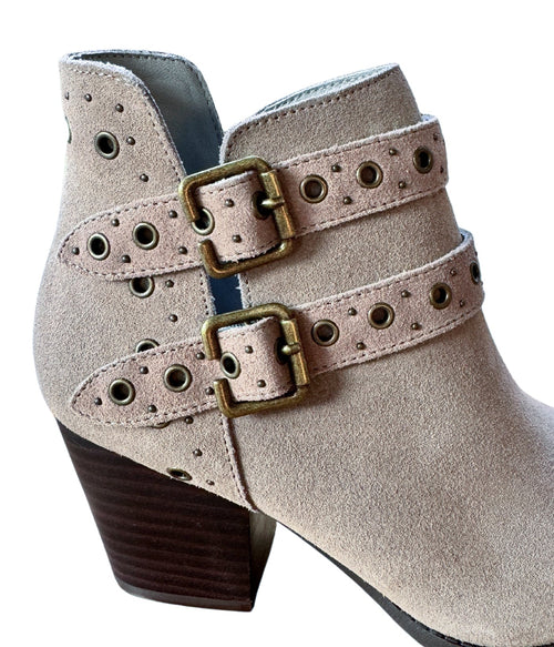 Close-up of brass grommets and buckle detail on taupe suede ankle boots