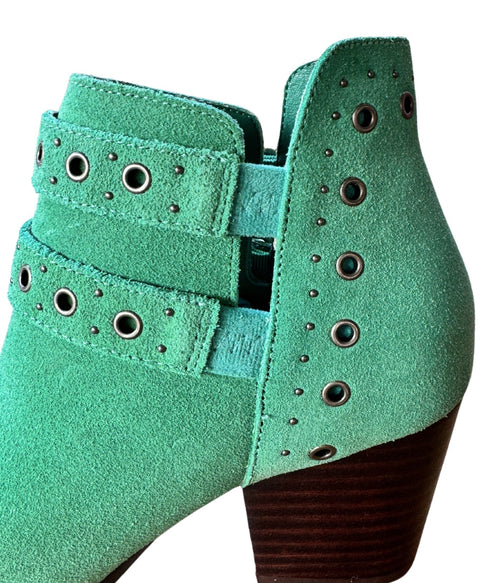 Close-up of brass grommets and buckle detail on teal suede ankle boots