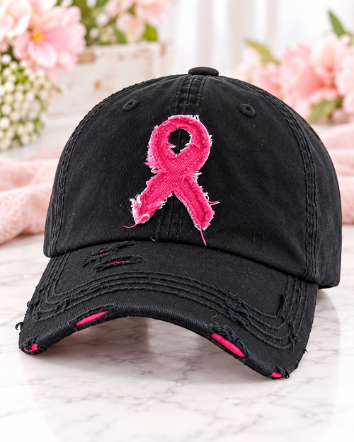 Woman wearing black distressed pink ribbon breast cancer awareness cap with cream sweater and jeans
